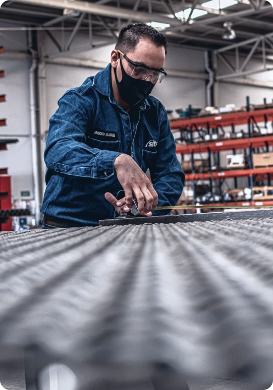Trabajador industrial con gafas de seguridad manipulando una malla para cribado